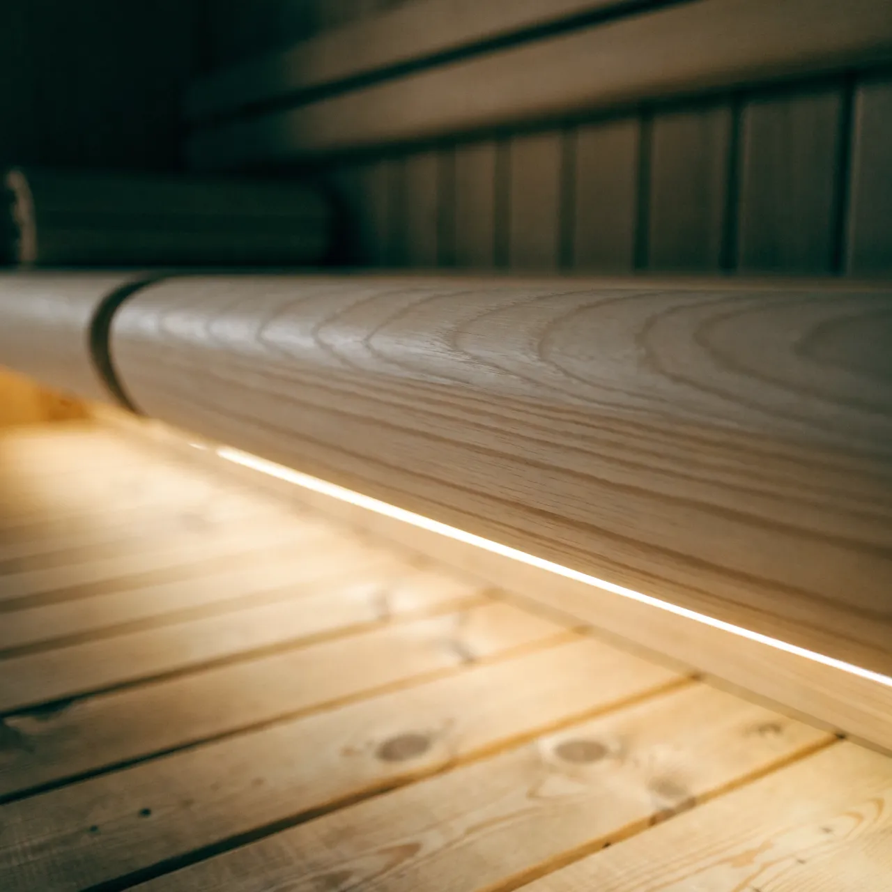 A pale timber bench with a warm light line beneath it