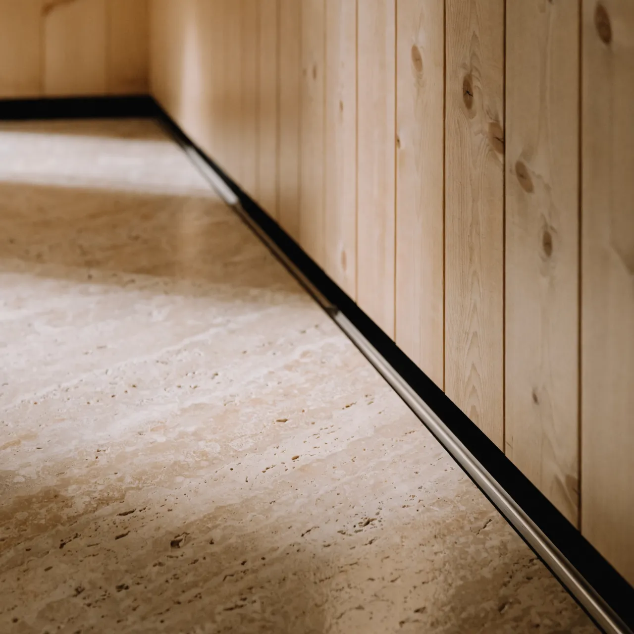 A honed travertine floor with a flush linear drain against a timber wall
