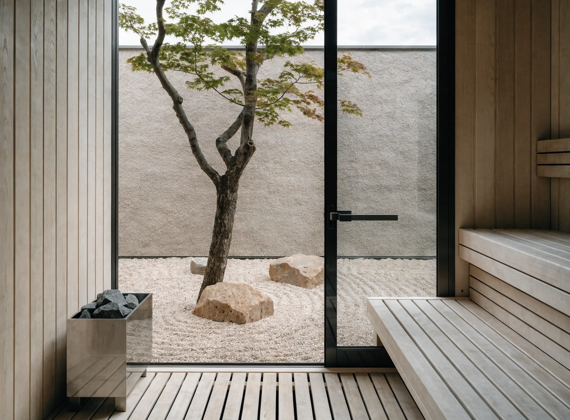 A sauna opening onto a raked gravel courtyard