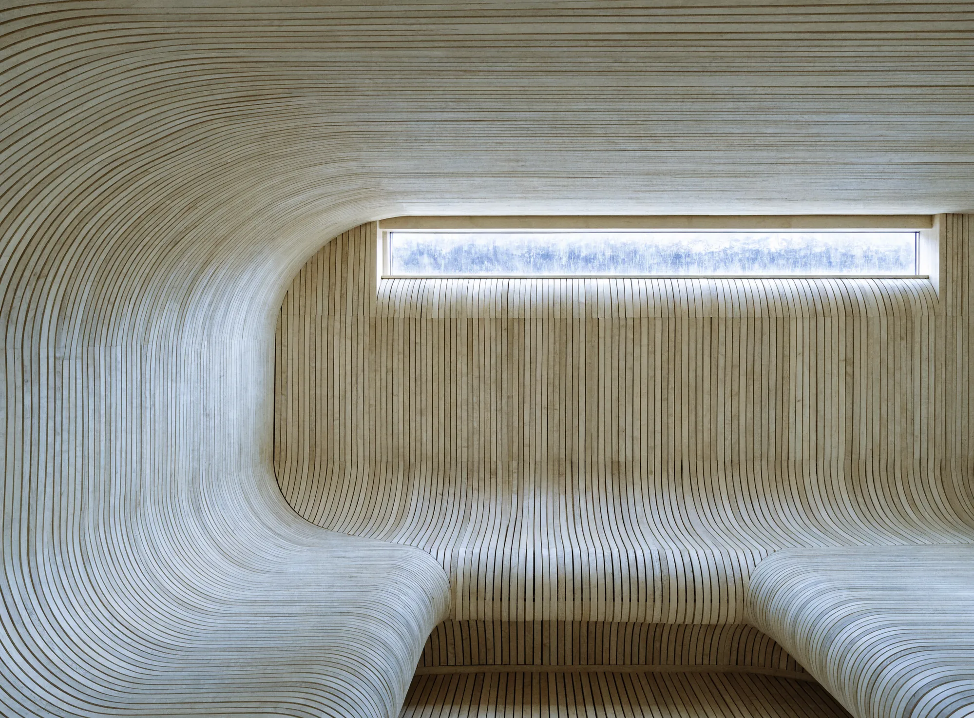 A sauna with curved timber walls and a continuous bench